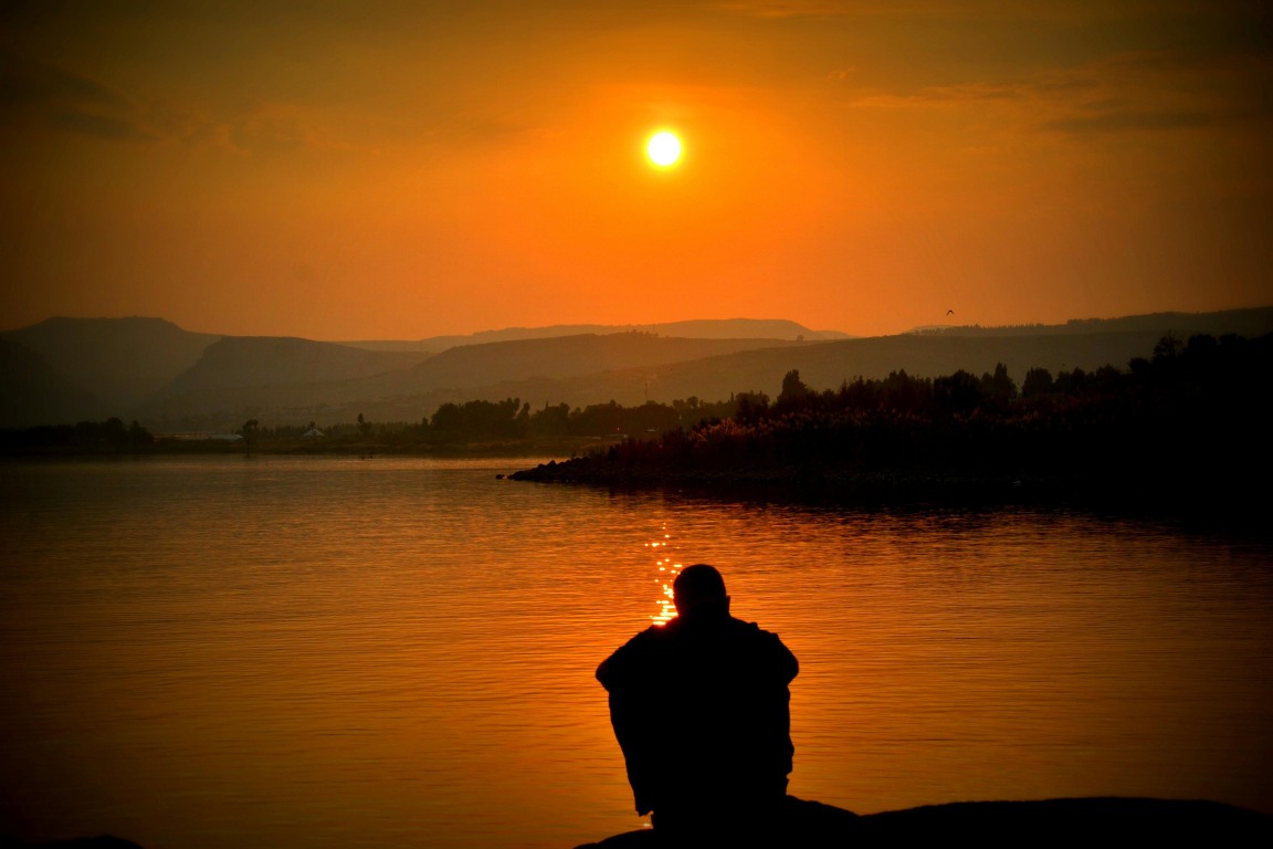 Person silhouette at sunset with arms spread wide